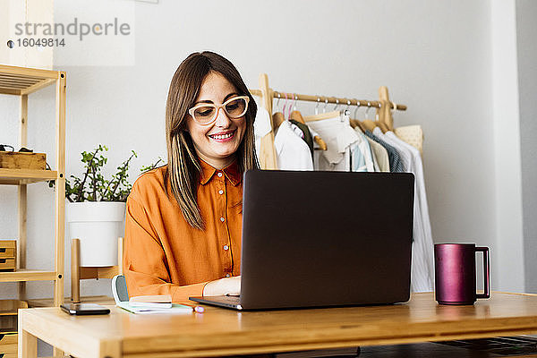 Modedesignerin arbeitet zu Hause am Schreibtisch mit Laptop