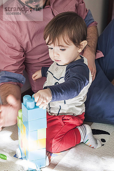 Kleiner Junge und Vater spielen zu Hause mit einem Plastikblock