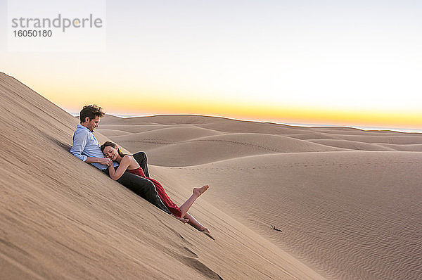 Glückliches Paar  das bei Sonnenuntergang in den Dünen liegt  Gran Canaria  Spanien