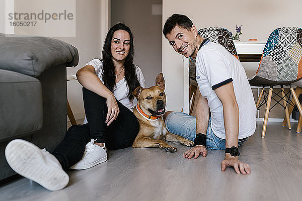 Mann und Frau sitzen mit Hund zu Hause auf dem Boden