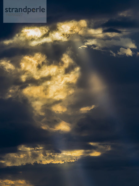 Sonnenlicht durchdringt dunkle Gewitterwolken