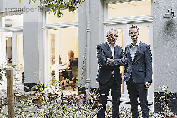 Zwei erfolgreiche Geschäftsleute stehen auf dem Hinterhof ihres Büros