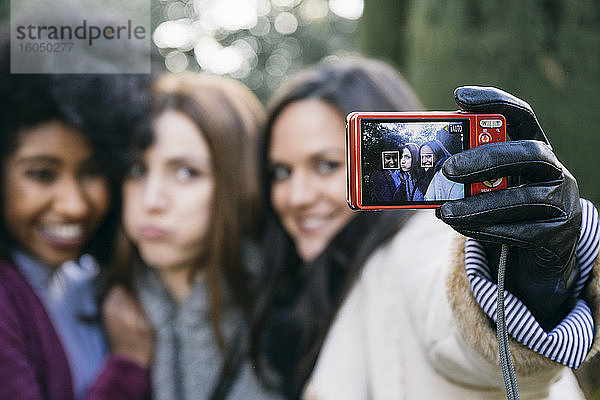 Nahaufnahme von Freundinnen  die im Winter ein Selfie mit der Kamera im Park machen