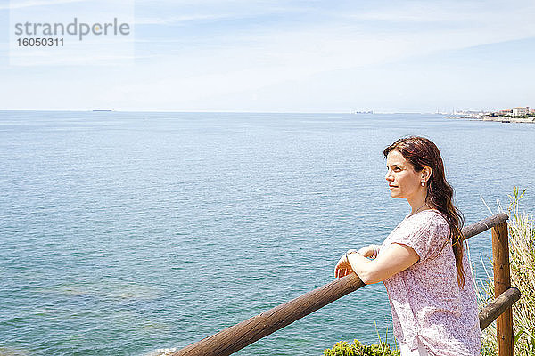 Frau lehnt an der Reling und schaut auf das Ligurische Meer gegen den Himmel an einem sonnigen Tag