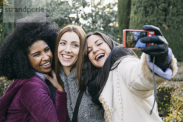 Fröhliche Freundinnen machen ein Selfie mit der Kamera  während sie im Park stehen