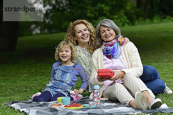 Fröhliche Frauen der dritten Generation genießen ein Picknick im öffentlichen Park