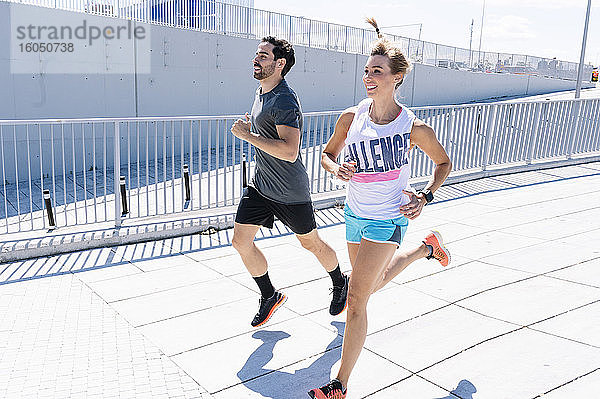 Glücklich fit Paar joggen auf der Straße der Stadt während des sonnigen Tages