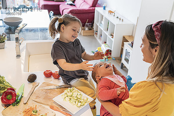 Glückliche Mutter und Tochter spielen mit Baby Mädchen in der Küche zu Hause