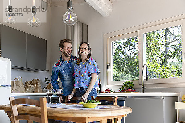 Lächelnde Frau mit Mann in der Küche zu Hause stehend