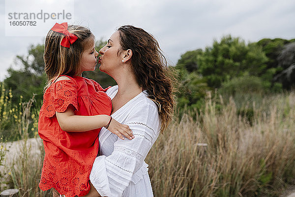 Zärtliche Mutter und Tochter küssen sich auf dem Lande