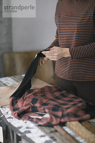 Nahaufnahme einer jungen Frau  die eine Platte auf einem Tisch in einem Atelier für Bekleidungsdesign hält
