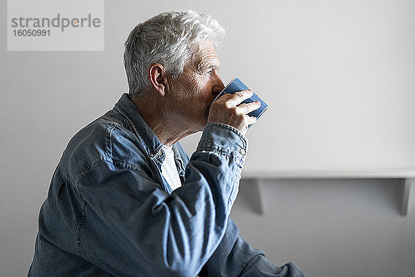 Nachdenklicher älterer Mann trinkt zu Hause Kaffee
