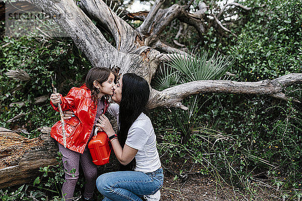 Mutter küsst ihre Tochter im Wald