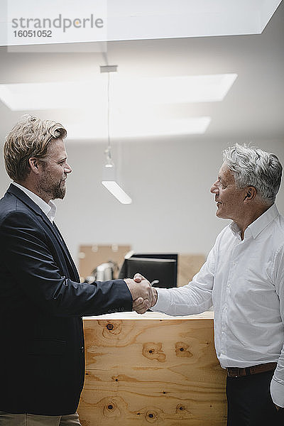 Geschäftspartner stehen im Büro und schütteln sich die Hände