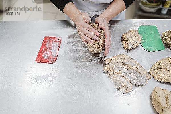 Bäckerin bei der Vorbereitung eines Brotlaibs auf dem Küchentisch in einer Bäckerei