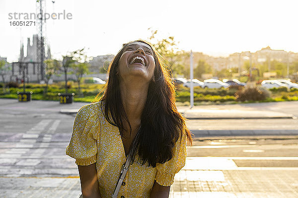 Fröhliche junge Frau auf der Straße in der Stadt an einem sonnigen Tag