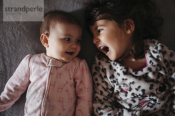 Mädchen schreit beim Anblick der süßen kleinen Schwester auf dem Bett