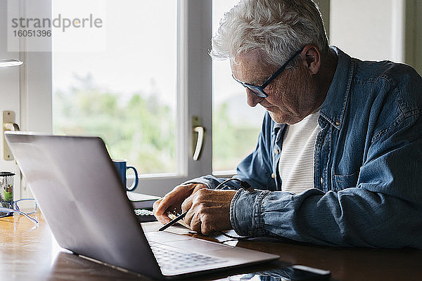 Älterer Mann repariert Laptop zu Hause