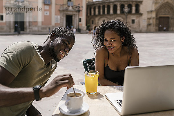 Glückliches Paar mit Laptop in einem Straßencafé