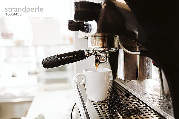 Kaffee wird aus einer Maschine in einer Bäckerei in eine Tasse gegossen