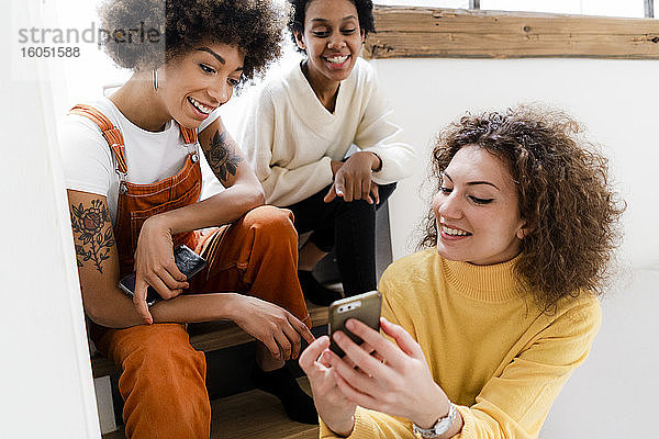 Drei Freunde haben Spaß mit dem Smartphone zu Hause