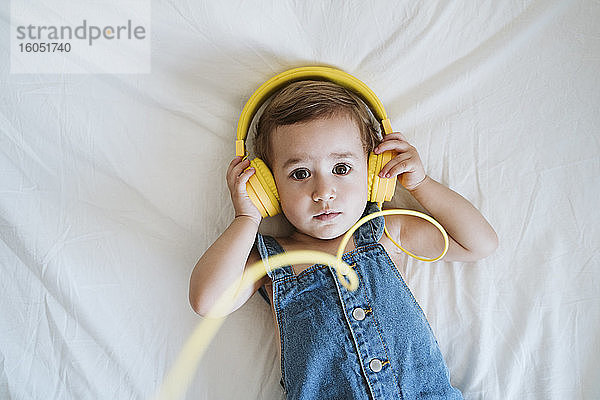 Kleines Mädchen zu Hause beim Musikhören im Bett