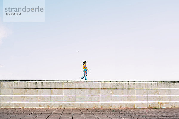 Junge Frau  die auf einer Mauer läuft