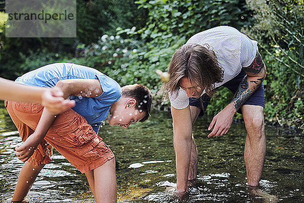 Mann erkundet mit Junge im Bachwasser im Wald