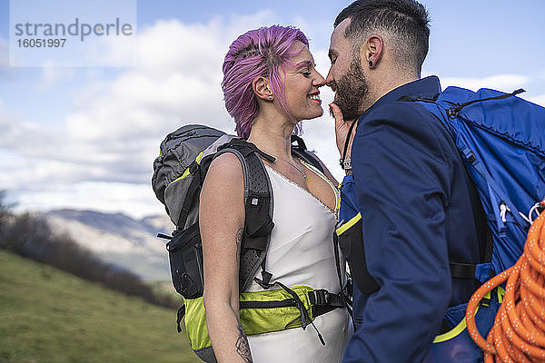 Küssendes Brautpaar mit Kletterrucksäcken auf dem Berg Urkiola  Spanien