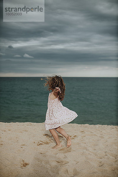 Unbekümmertes Mädchen tanzt auf Sand gegen das Meer