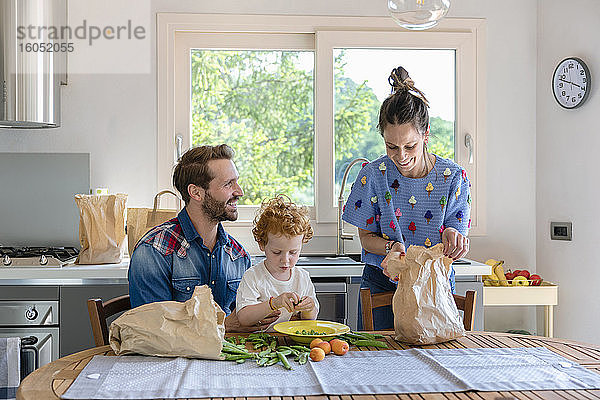 Junge mit lächelnden Eltern in der Küche zu Hause