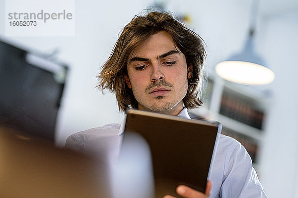 Nahaufnahme eines männlichen Berufstätigen  der ein digitales Tablet benutzt  während er in einem Café sitzt