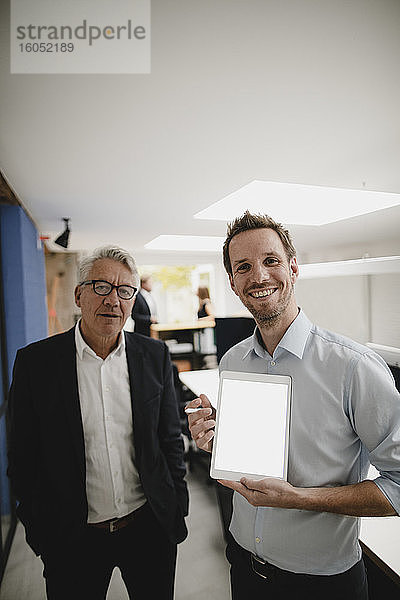 Zwei erfolgreiche Geschäftsleute stehen im Büro und benutzen ein digitales Tablet
