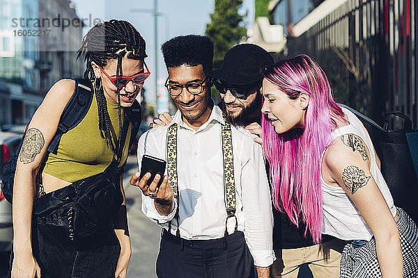 Eine Gruppe von Freunden teilt sich ein Smartphone in der Stadt