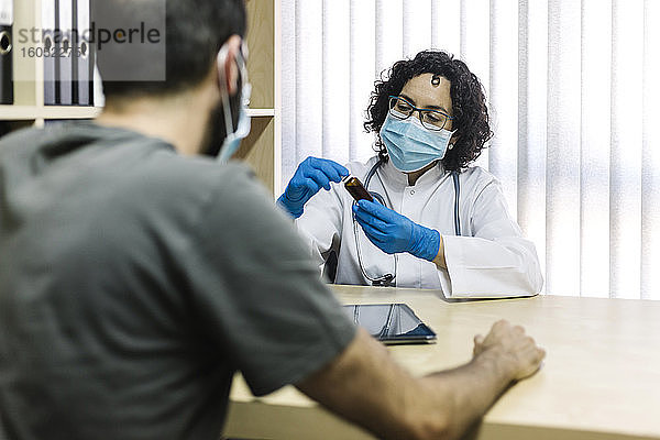 Weiblicher Arzt bespricht Medizin mit Patient im Büro in der Klinik