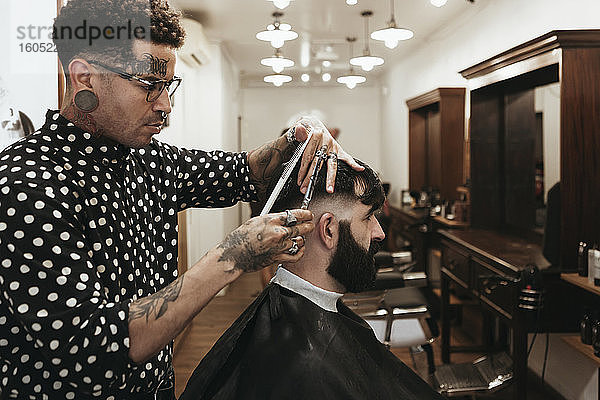 Modischer Friseur stylt Männerhaar im Salon