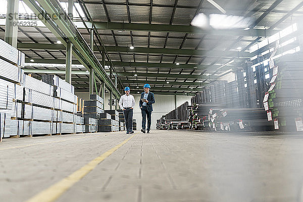 Zwei Geschäftsleute bei einem Treffen und einem Spaziergang in einer Fabrik