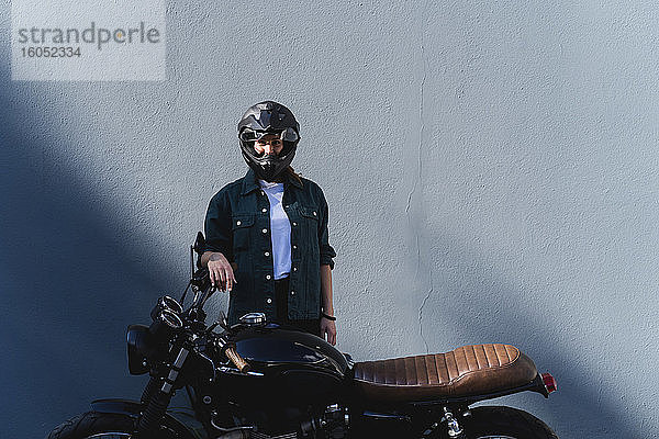 Frau mit Helm am Motorrad stehend