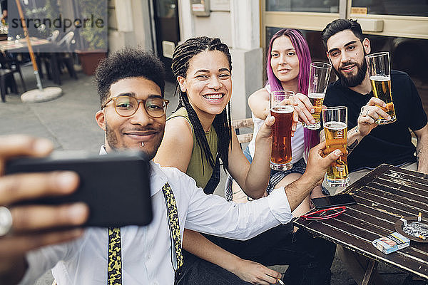 Glückliche Freunde  die Biergläser halten und ein Selfie in einer Bar machen