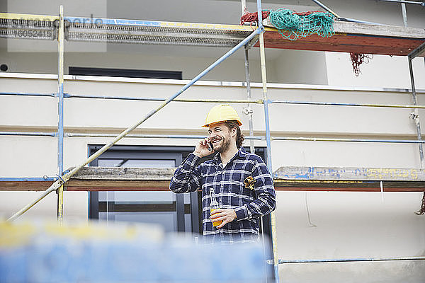 Lächelnder Arbeiter am Telefon auf einer Baustelle