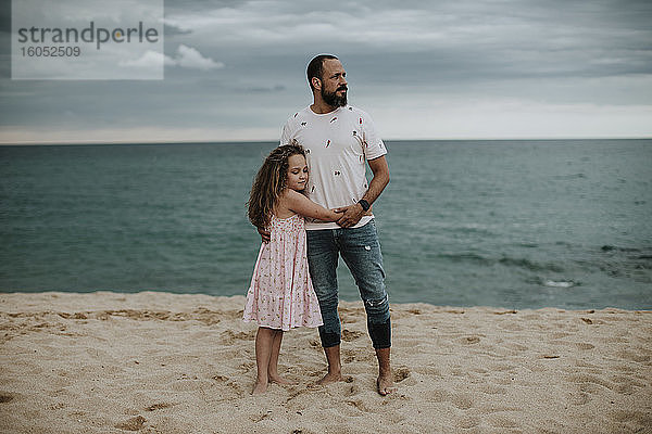 Tochter umarmt Vater am Strand