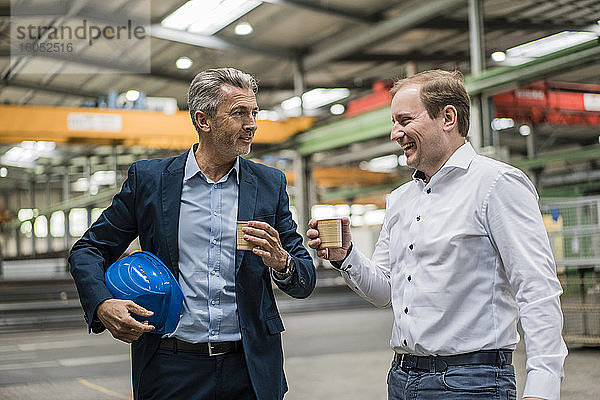 Zwei Geschäftsleute bei einer Kaffeepause in einer Fabrik