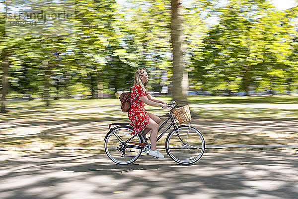 Unscharfe Bewegung einer Fahrrad fahrenden Frau auf einem Fußweg in einem öffentlichen Park