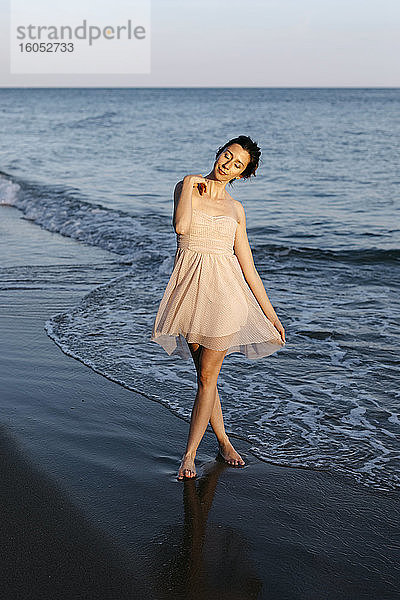 Zarte Ballerina tanzt bei Sonnenuntergang am Strand