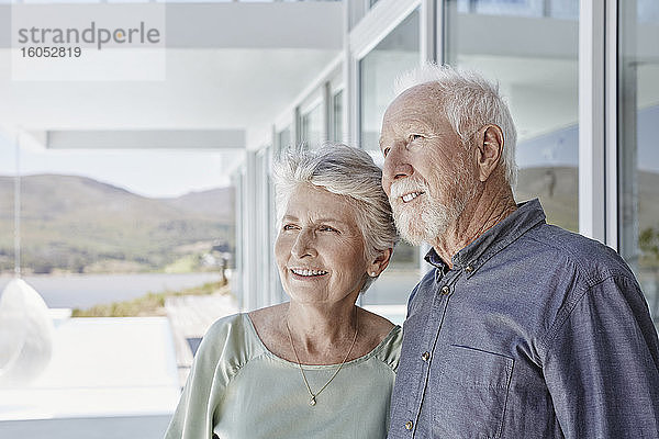 Porträt eines lächelnden älteren Paares in einem luxuriösen Strandhaus