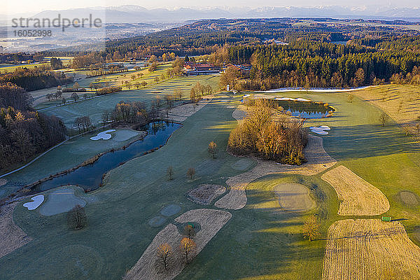 Deutschland  Bayern  Wolfratshausen  Drohnenansicht eines ländlichen Golfplatzes in der Dämmerung