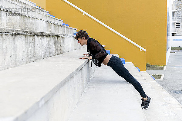 Sportliche Frau beim Plankentraining auf der Treppe