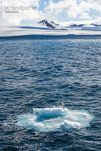 Im Wasser schwimmendes Eis mit der Küstenlinie der Tabarin-Halbinsel im Hintergrund
