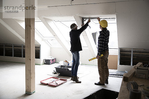 Architekt und Bauarbeiter diskutieren über Fensterrahmen bei der Renovierung eines Hauses