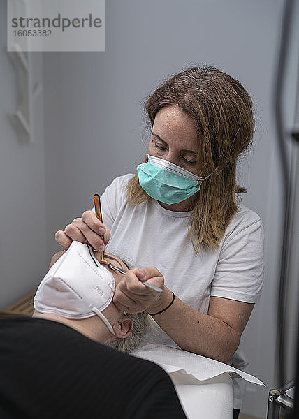 Kosmetikerin bei der Anwendung von Werkzeugen zur Wimpernverlängerung bei einer Kundin im Schönheitssalon